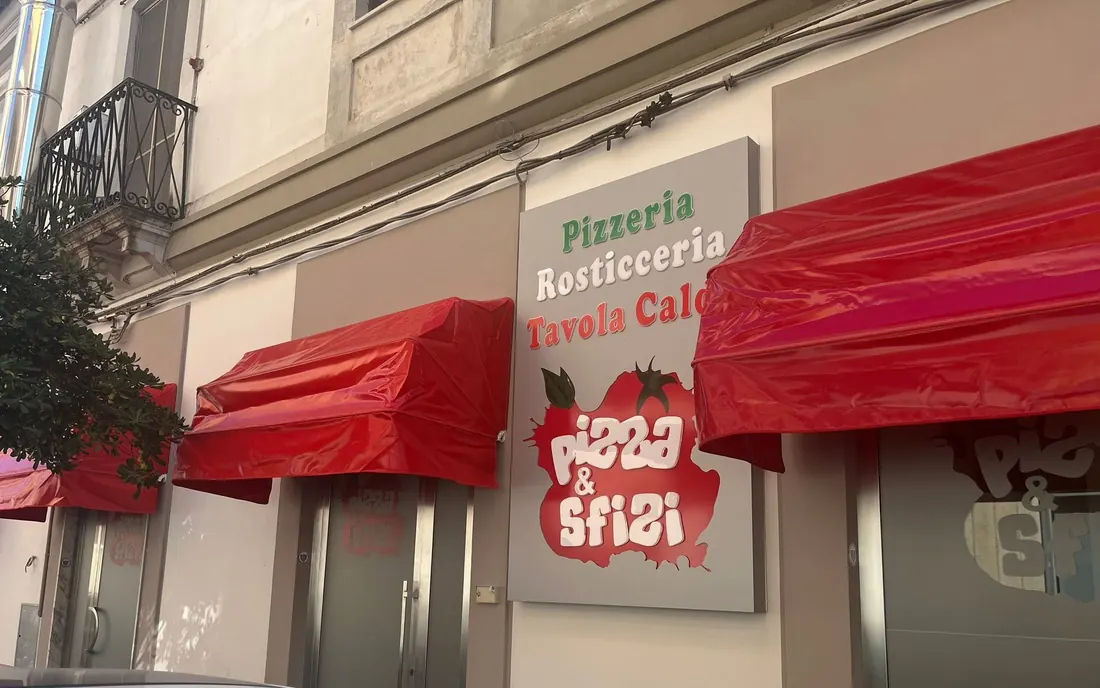 L'esterno di Pizza & Sfizi in Via Tommaso Gulli: le tende rosse e l'insegna Pizzeria, Rosticceria, Tavola calda