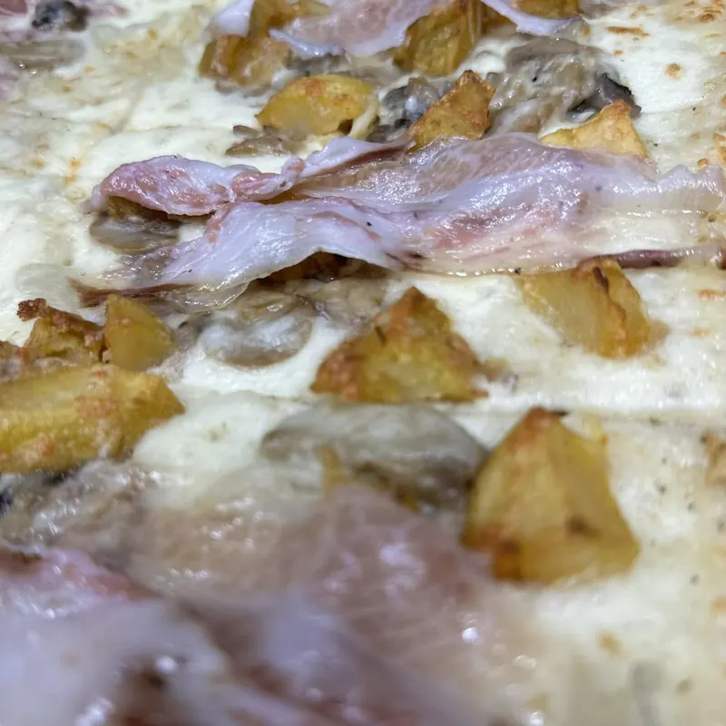 Un pezzo di teglia bianca con patate, funghi porcini e lardo