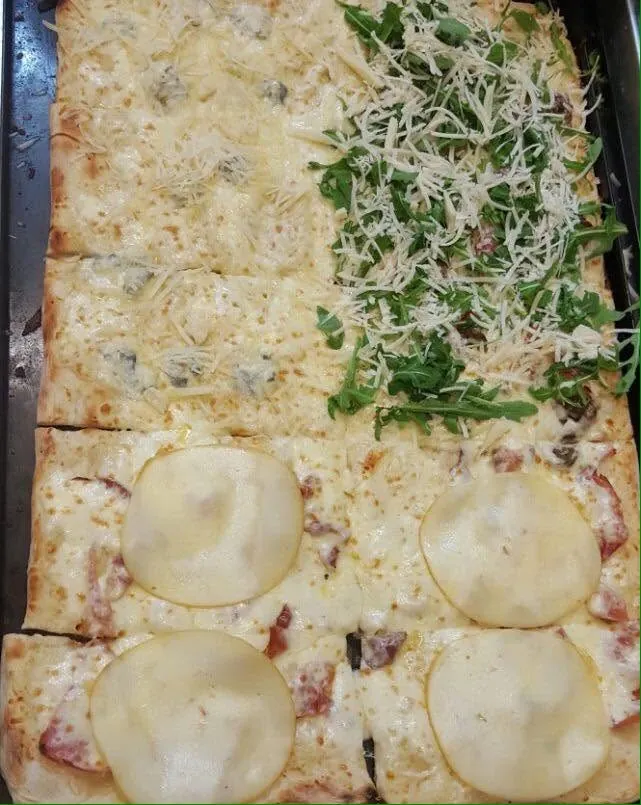 Una teglia bianca già tagliata in pezzi, con tre gusti diversi